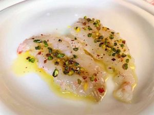 Carpaccio di scampi con bacche rosa e granella di pistacchi 