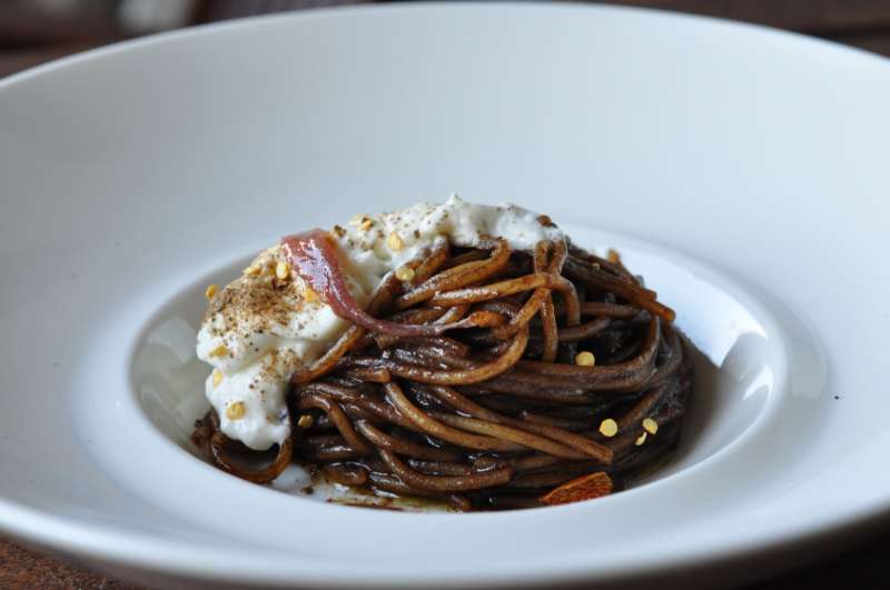 Golosaria e una ricetta: Spaghetto all’aglio nero di Aomori, burrata, capperi e acciughe da una ricetta di Andrea Bertarini